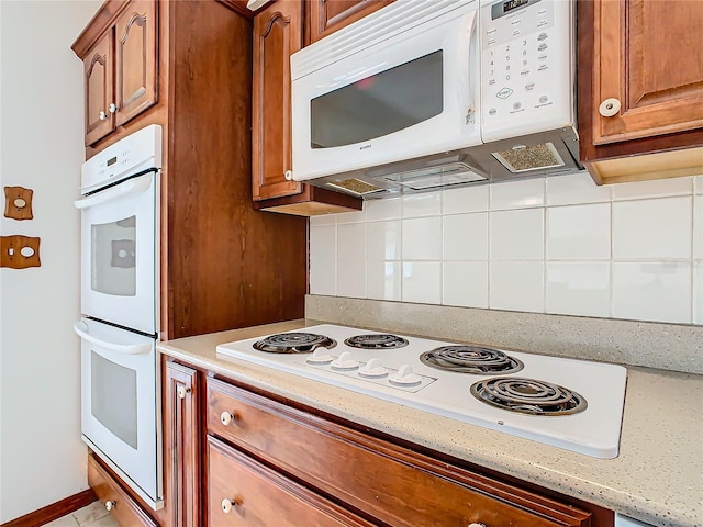 kitchen with backsplash, light stone counters, and white appliances