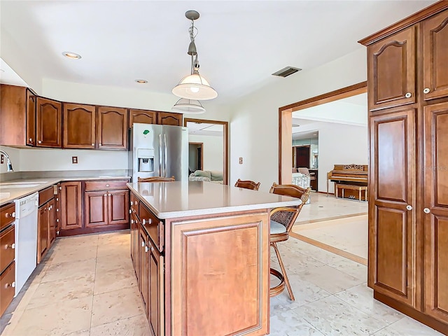 kitchen featuring dishwasher, stainless steel fridge, decorative light fixtures, a breakfast bar, and a kitchen island