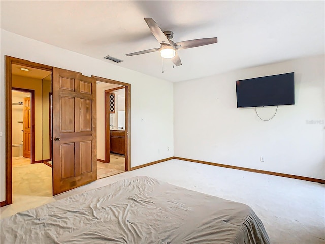 bedroom featuring ceiling fan, light colored carpet, and ensuite bathroom