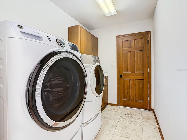 laundry area featuring washer and dryer, light tile patterned floors, and cabinets