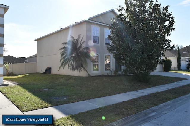 view of property exterior featuring driveway, stucco siding, fence, a lawn, and a garage