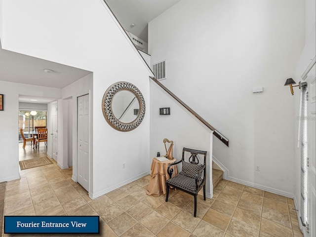staircase featuring a high ceiling, baseboards, and visible vents