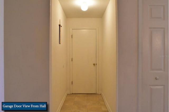 hallway featuring light tile patterned floors and baseboards