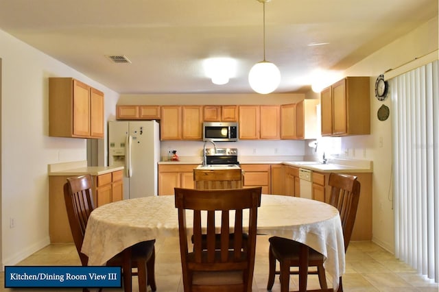 kitchen with light countertops, a sink, pendant lighting, stainless steel appliances, and visible vents