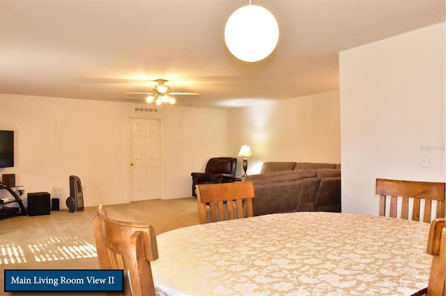 carpeted dining room with ceiling fan and visible vents