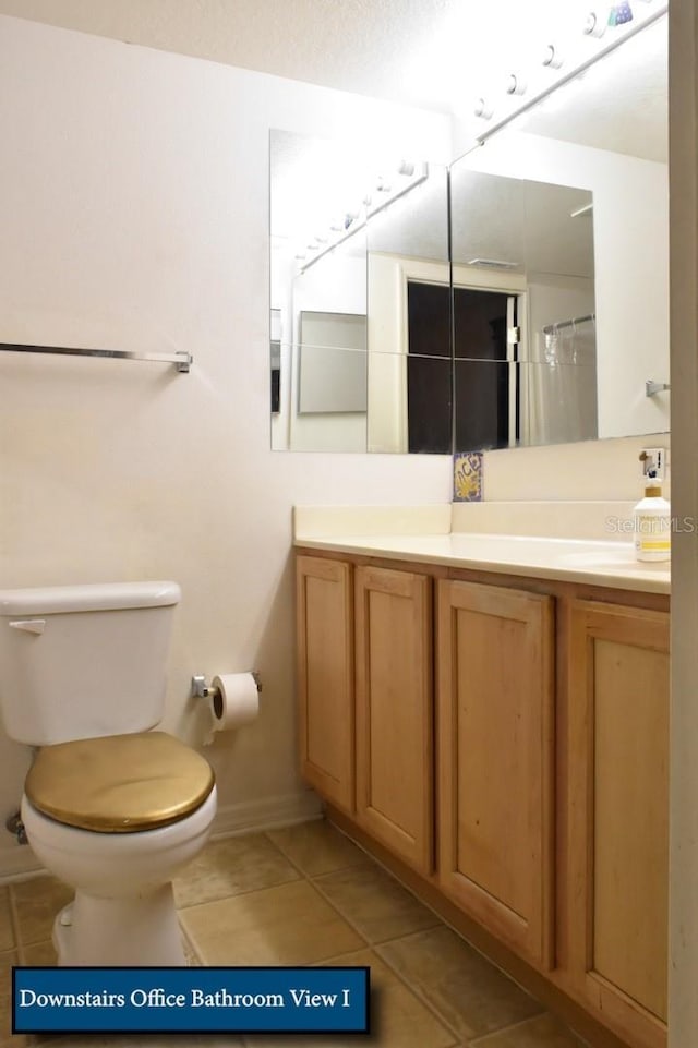 bathroom featuring tile patterned flooring, vanity, toilet, and baseboards