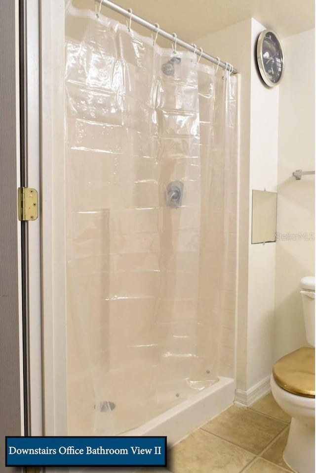 bathroom featuring baseboards, toilet, tile patterned flooring, and a shower stall