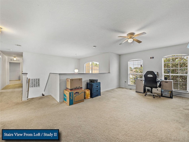 home office featuring a textured ceiling, visible vents, carpet, and a ceiling fan