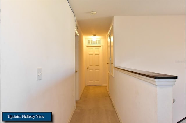 hall with baseboards, visible vents, and light carpet