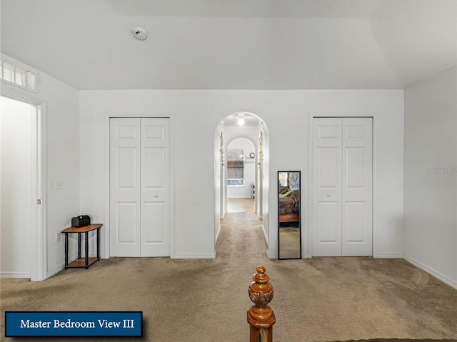 unfurnished bedroom featuring carpet floors and arched walkways