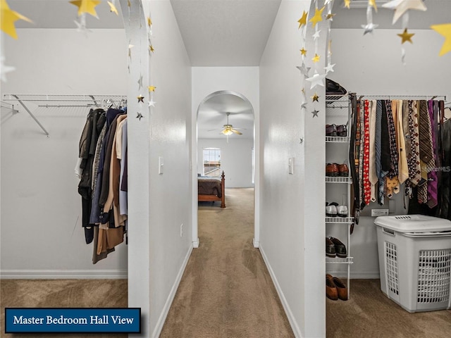 spacious closet featuring arched walkways, ceiling fan, and carpet