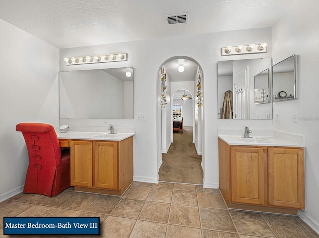 ensuite bathroom with connected bathroom, visible vents, a sink, and two vanities