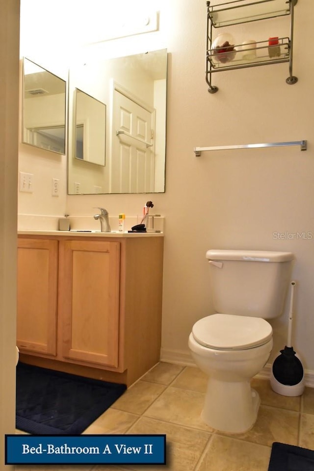 half bathroom featuring baseboards, toilet, tile patterned floors, and vanity