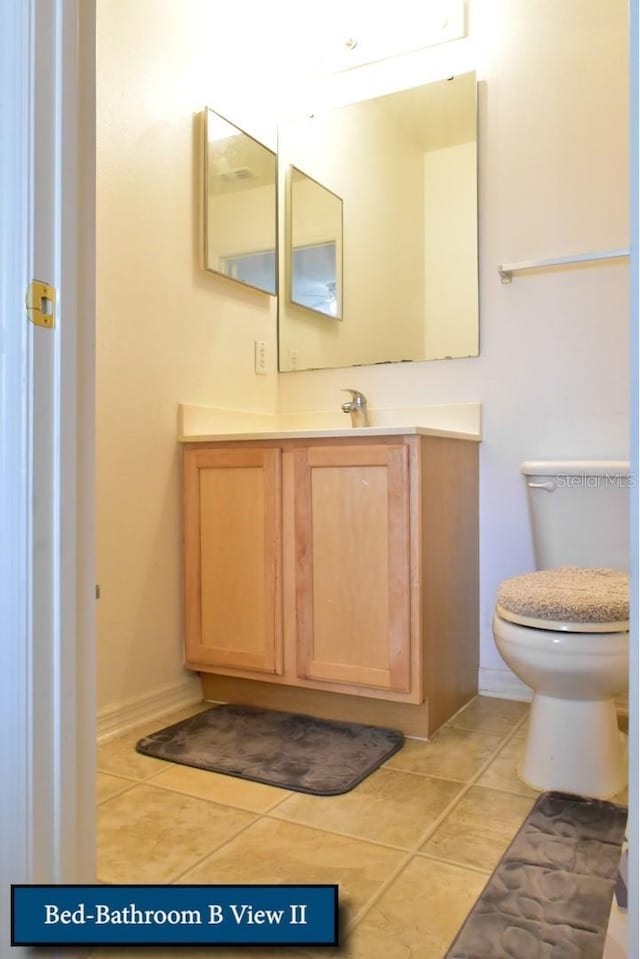 half bathroom featuring tile patterned floors, toilet, and vanity