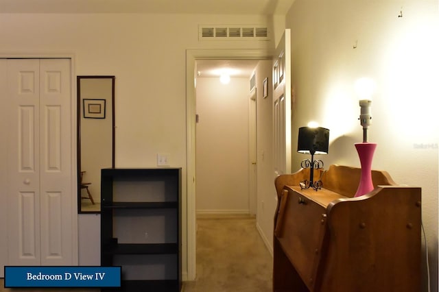 hallway with carpet floors, baseboards, and visible vents