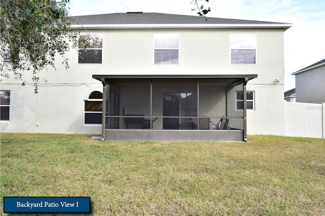 rear view of property featuring a lawn, stucco siding, a sunroom, and fence