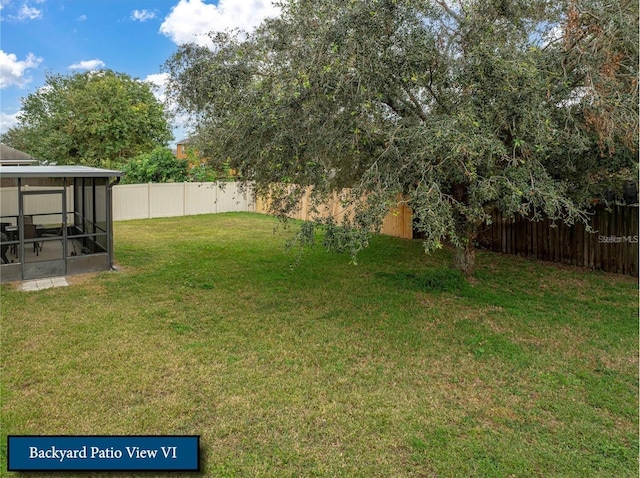 view of yard with a sunroom and a fenced backyard
