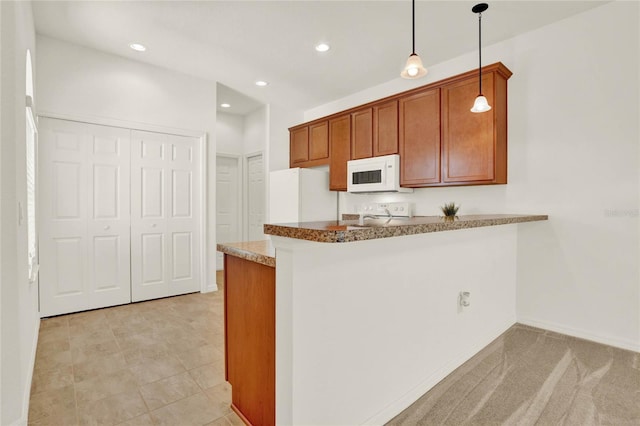 kitchen featuring kitchen peninsula, decorative light fixtures, light carpet, and white appliances