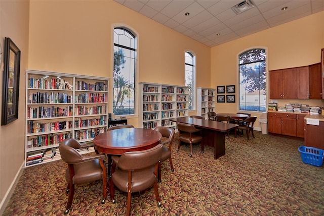 dining area featuring a drop ceiling, a wealth of natural light, and a high ceiling