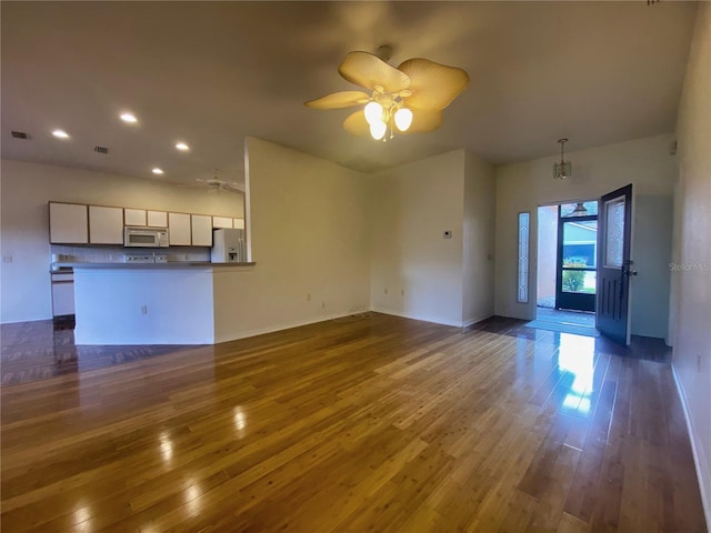 unfurnished living room featuring ceiling fan and dark wood-type flooring