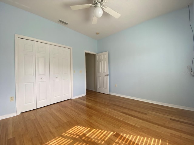 unfurnished bedroom with hardwood / wood-style floors, a closet, and ceiling fan