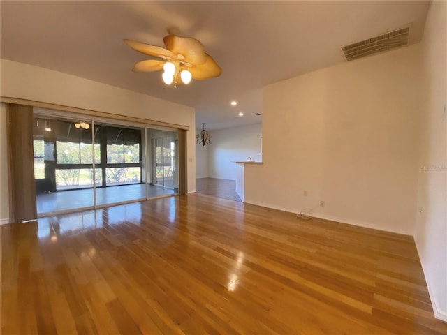 unfurnished room featuring hardwood / wood-style floors and ceiling fan with notable chandelier