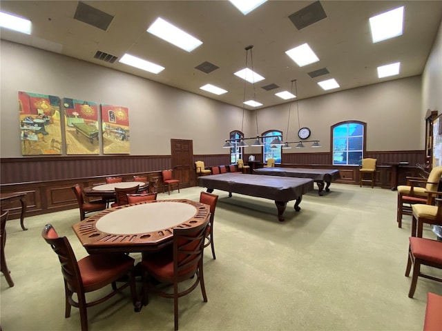 rec room with wood walls, a towering ceiling, light carpet, and pool table