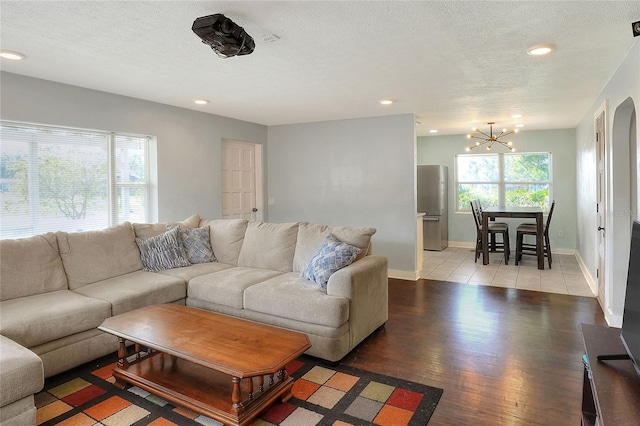 living room featuring light wood-type flooring, a textured ceiling, and an inviting chandelier