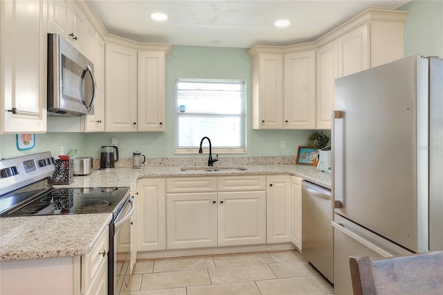 kitchen with appliances with stainless steel finishes, a sink, light tile patterned floors, recessed lighting, and light stone counters