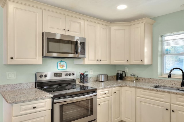 kitchen with stainless steel appliances, a sink, and light stone counters