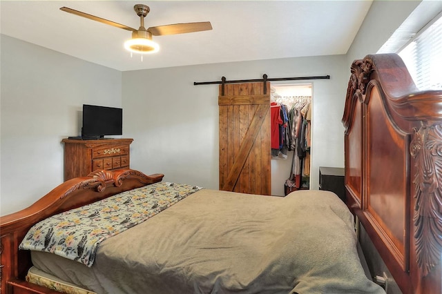 bedroom with a barn door, ceiling fan, a closet, and a spacious closet