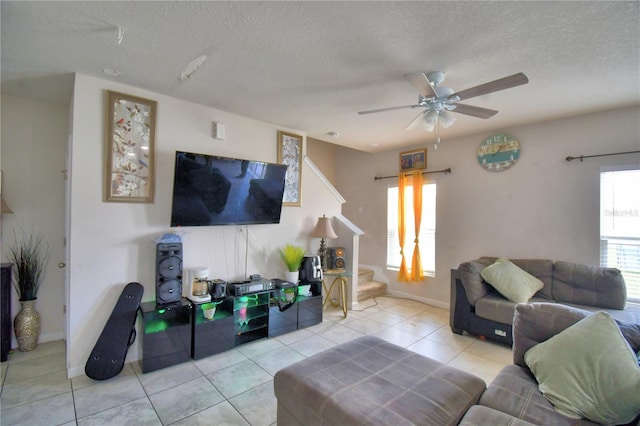 living room featuring a textured ceiling, light tile patterned floors, and ceiling fan