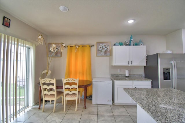 kitchen featuring refrigerator, white cabinets, stainless steel refrigerator with ice dispenser, light tile patterned floors, and light stone countertops