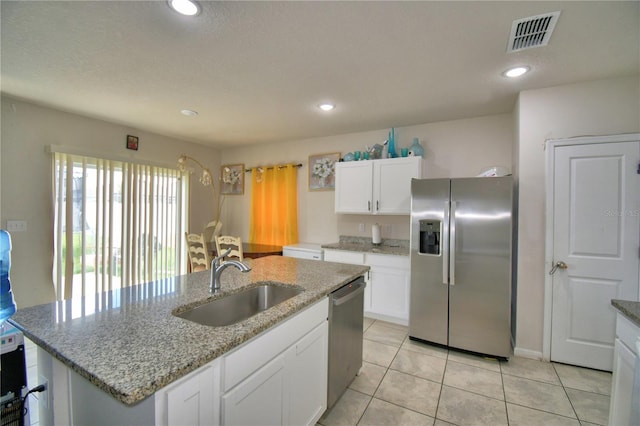 kitchen with stainless steel appliances, a center island with sink, light stone counters, sink, and white cabinetry