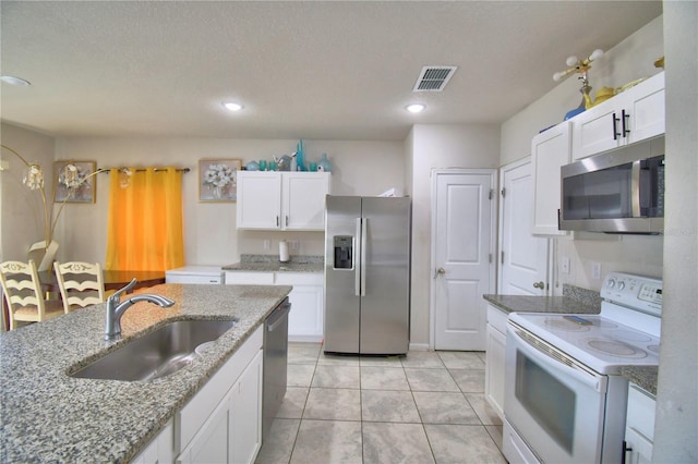 kitchen featuring stainless steel appliances, light tile patterned floors, sink, stone countertops, and white cabinetry