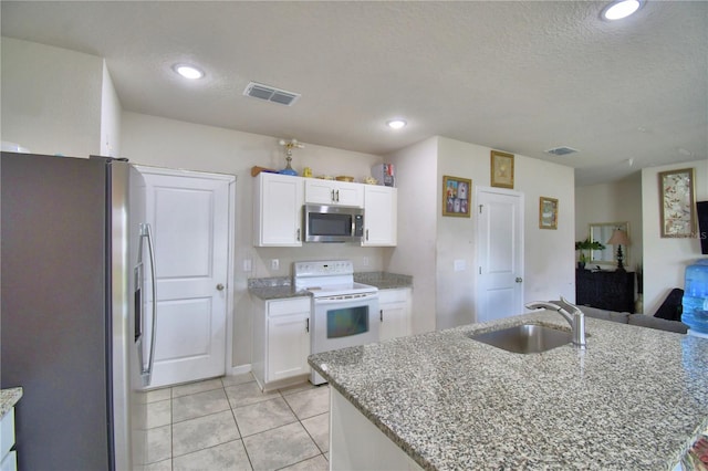 kitchen with white cabinets, appliances with stainless steel finishes, a center island with sink, and sink