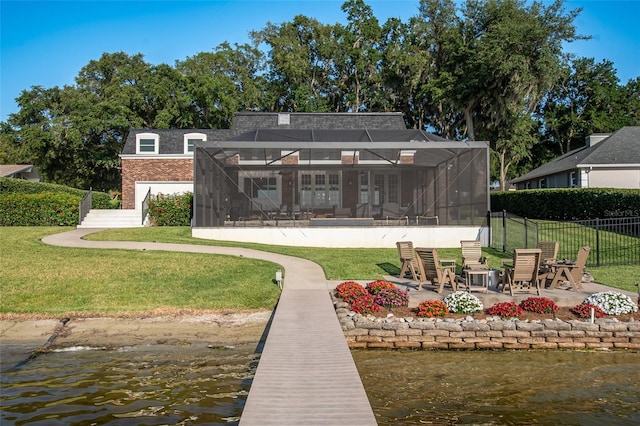 rear view of house featuring a fire pit, a water view, a lanai, a yard, and a patio area