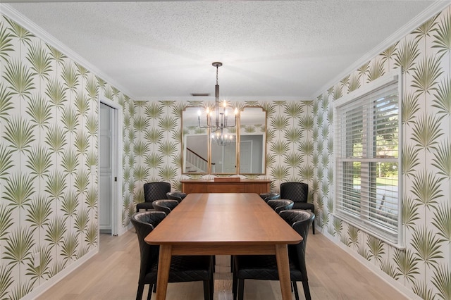 dining area with ornamental molding, light wood-type flooring, a textured ceiling, and an inviting chandelier