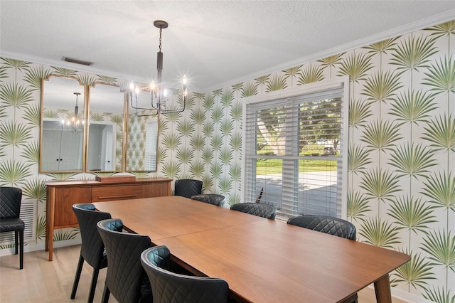 dining area with crown molding, a chandelier, a textured ceiling, and light wood-type flooring