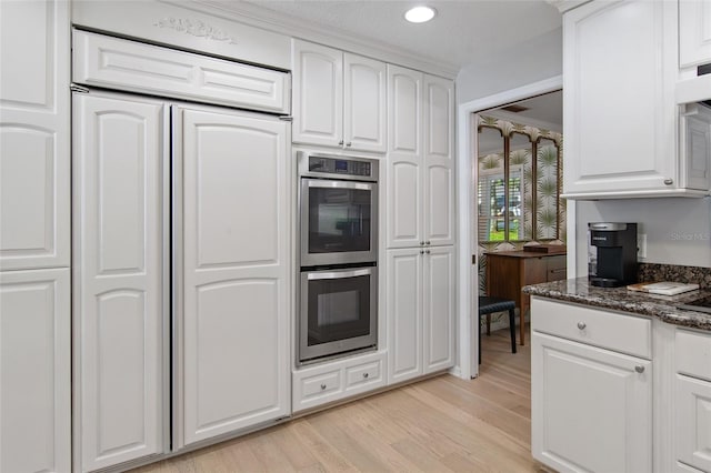 kitchen with dark stone countertops, a textured ceiling, double oven, light hardwood / wood-style floors, and white cabinetry