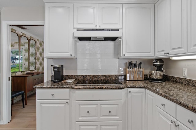 kitchen with black electric cooktop, white cabinets, dark stone counters, and light hardwood / wood-style floors