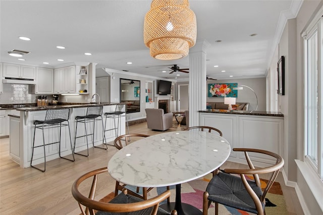 dining room with light hardwood / wood-style floors, crown molding, ceiling fan, and a healthy amount of sunlight