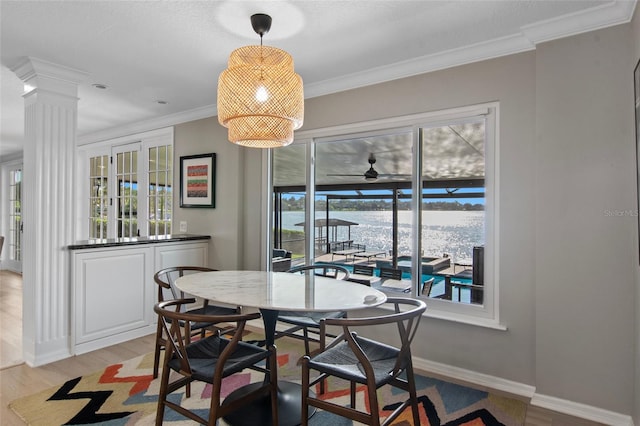 dining space with decorative columns, ceiling fan, light hardwood / wood-style floors, and ornamental molding