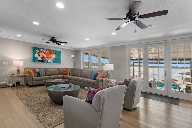 living room featuring hardwood / wood-style flooring, ceiling fan, ornamental molding, and a textured ceiling