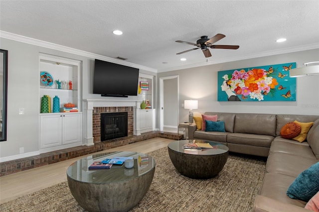 living room with hardwood / wood-style floors, ceiling fan, ornamental molding, a fireplace, and a textured ceiling