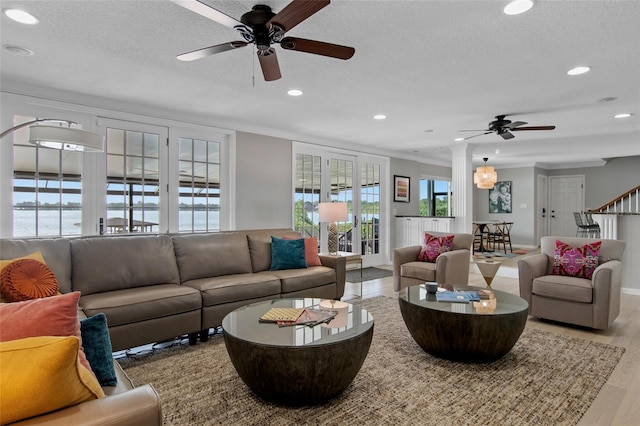 living room with a water view, light hardwood / wood-style flooring, a wealth of natural light, and ceiling fan