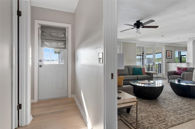 hall with a textured ceiling, light hardwood / wood-style floors, and ornamental molding