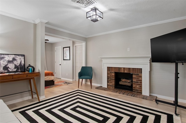 living room featuring a textured ceiling, light wood-type flooring, a brick fireplace, and ornamental molding