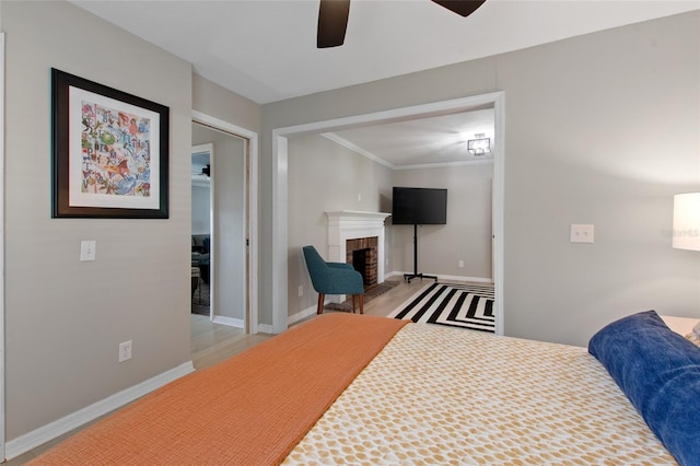 bedroom with ceiling fan, a fireplace, crown molding, and light hardwood / wood-style flooring