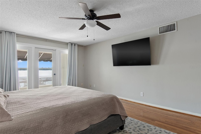 bedroom with access to exterior, ceiling fan, hardwood / wood-style floors, and a textured ceiling